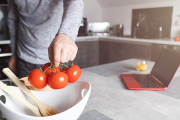 Pomidory na gałązce wkładane do miski w kuchni przez mężczyzne. - obrazy, fototapety, plakaty