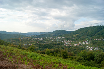 Obraz premium Mountain landscape - summer, mountains, sky and small houses in the lowlands.