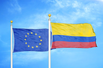 European Union and Colombia two flags on flagpoles and blue cloudy sky