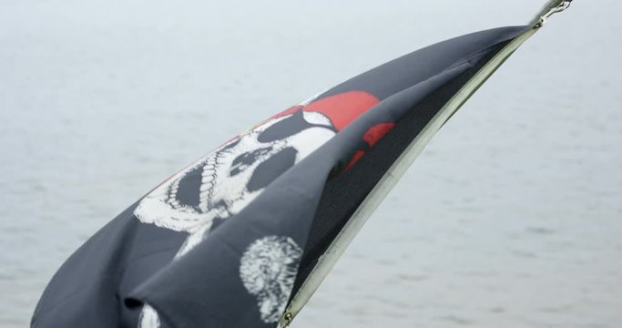 Pirate flag blowing in wind on ocean - slowly zooming in