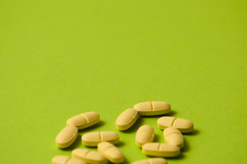 Many yellow pills on a green background with room for copy space