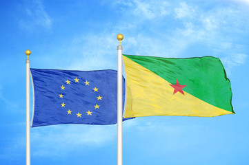 European Union and French Guiana two flags on flagpoles and blue cloudy sky