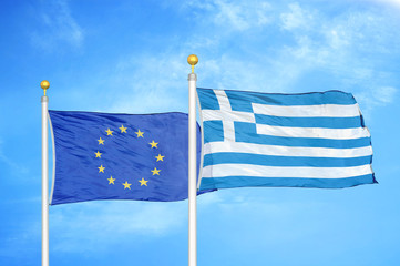 European Union and Greece two flags on flagpoles and blue cloudy sky