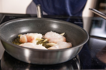 hands of cook preparing food in a frying pan
