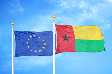 European Union and Guinea-Bissau two flags on flagpoles and blue cloudy sky
