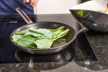 hands of cook preparing food in a frying pan