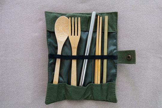 Reusable and environmentally friendly utensils, including bamboo spoon, fork, chopsticks, small straw and one big stainless steel straw in a folded cloth bag.