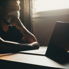 Obraz premium A asian man in medical mask working on laptop in dark area. Thinking gesture.