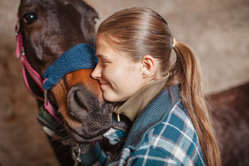 
A girl in a blue checkered trowel with a tail of hair on her head loves her horse, takes care of...