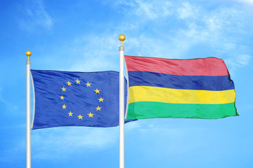 European Union and Mauritius two flags on flagpoles and blue cloudy sky