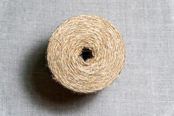 Isolated roll of jute twine over natural linen texture background. Hank of twine closeup. 