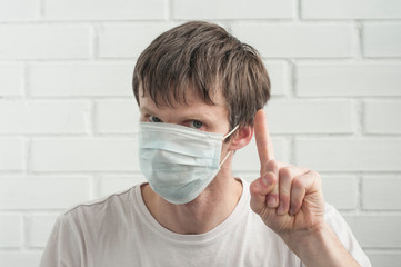 Man wearing a protective medical mask and holding up his index fingerinfectious diseases. Stop coronavirus concept.