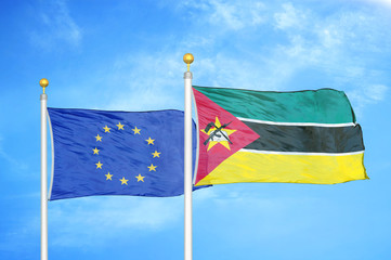 European Union and Mozambique two flags on flagpoles and blue cloudy sky