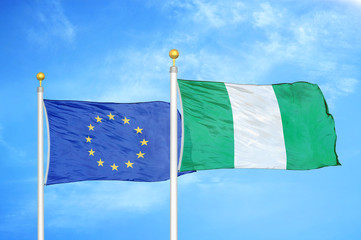 European Union and Nigeria two flags on flagpoles and blue cloudy sky