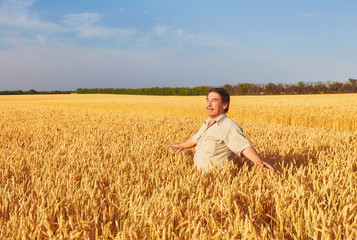 Satisfied mature farmer touching with care his ripe wheat field