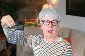 Surprised senior woman holding calculator 