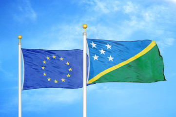 European Union and Solomon Islands two flags on flagpoles and blue cloudy sky