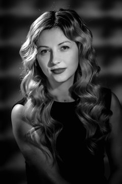 Fashion studio portrait of beautiful girl with blonde curly hair. image in black and white conversion