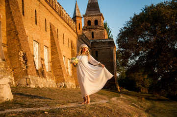 blonde girl in a white dress on nature near architectural monuments in the open air