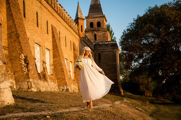 Obraz premium blonde girl in a white dress on nature near architectural monuments in the open air