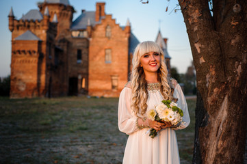 Obraz premium blonde girl in a white dress on nature near architectural monuments in the open air