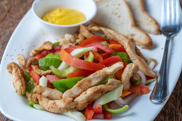 Roasted chicken fillet with vegetables and bread on a white plate, closeup