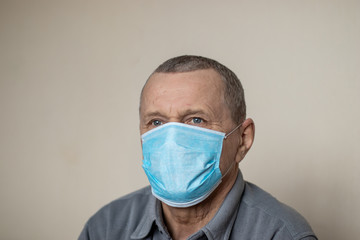 Old man with sad and scared eyes wearing medical mask during COVID-19 coronavirus pandemia, in self isolation, virus epidemy, pneumonia and cough concept
