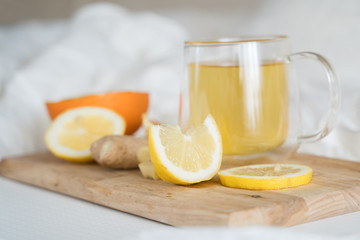Cup with antipyretic drugs for colds,flu.Tea with citrus vitamin C,ginger root,lemon,orange.Wooden tray in patient's bed. Home self-treatment.Medical quarantine antiviral covid-19 coronavirus therapy