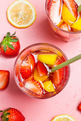 Fresh strawberry lemonade with lemon in glasses on pink background
