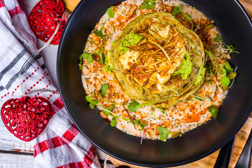 A dish of vegetable patties, Halloumi and Avocado, stacked up on a dark blue plate.
