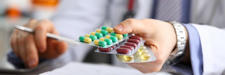 GP in clinic holding pack of different blisters
