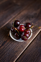 Cherries in a white bowl on wooden suface