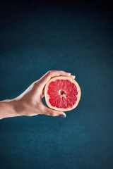 Hand holding the grapefruit on a blue background