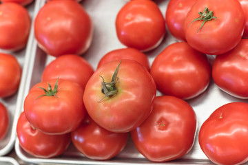 Ripe organic beefsteak tomatoes on metal tray at local market in Texas, America
