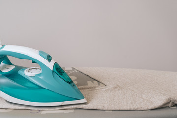 Iron disinfection of clothes. The iron is on the ironing board. Ironing process.