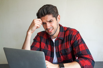 Young attractive man entrepreneur is slowing a problem on his laptop on the desk