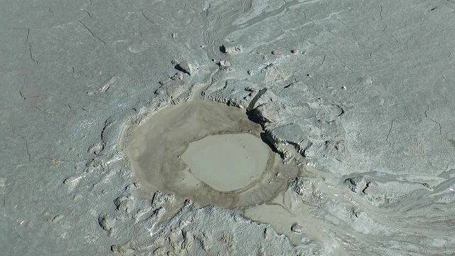 Mud volcano. A crater erupted mud out of liquid clay.