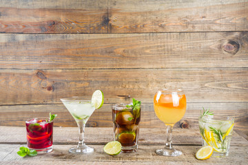 

Selection of summer alcohol drinks - mocktails and cocktails. Aperol spritz, Cube libre, Gimlet martini, mojito, sangria. Various cold summer bar and party beverages on wooden background copy space
