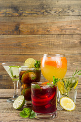 

Selection of summer alcohol drinks - mocktails and cocktails. Aperol spritz, Cube libre, Gimlet martini, mojito, sangria. Various cold summer bar and party beverages on wooden background copy space
