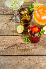 

Selection of summer alcohol drinks - mocktails and cocktails. Aperol spritz, Cube libre, Gimlet martini, mojito, sangria. Various cold summer bar and party beverages on wooden background copy space
