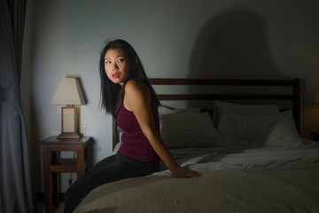 young scared and depressed Asian Chinese woman suffering anxiety disorder and depression problem crying on bed in panic about covid-19 quarantine home lockdown
