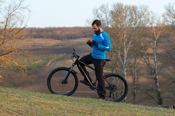 Fototapeta premium Cyclist in pants and fleece jacket on a modern carbon hardtail bike with an air suspension fork. The guy on the top of the hill rides a bike.