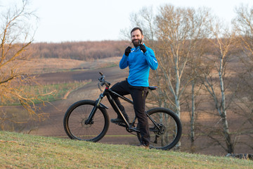 Fototapeta premium Cyclist in pants and fleece jacket on a modern carbon hardtail bike with an air suspension fork. The guy on the top of the hill rides a bike.