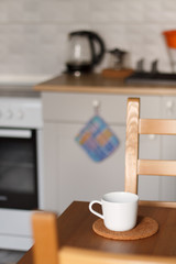 white mug against the kitchen background on the table with a blurred background. composition kitchen