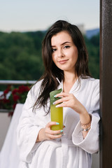 Beautiful girl in bathrobe relax on the hotel balcony with beautiful view on mountains