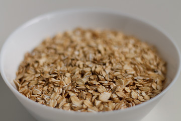 close-up of raw oatmeal on a white plate on a light background. vegetarian food.