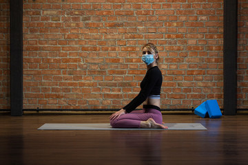 Young russian girl in yoga pose in medical mask