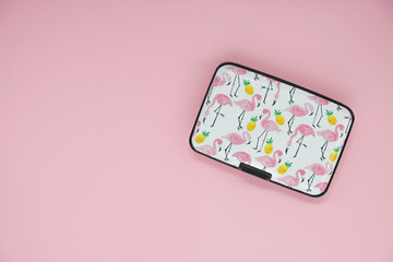Metal box with pink flamingos on pink background. Copy space. Minimalism.