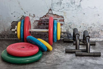 Professional dumbbells, multi-colored weight plates and push-up stops on a vintage background. Sports equipment. Healthy lifestyle.