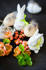 Easter background with decorative Easter eggs, rabbits and blossoming spring branch.